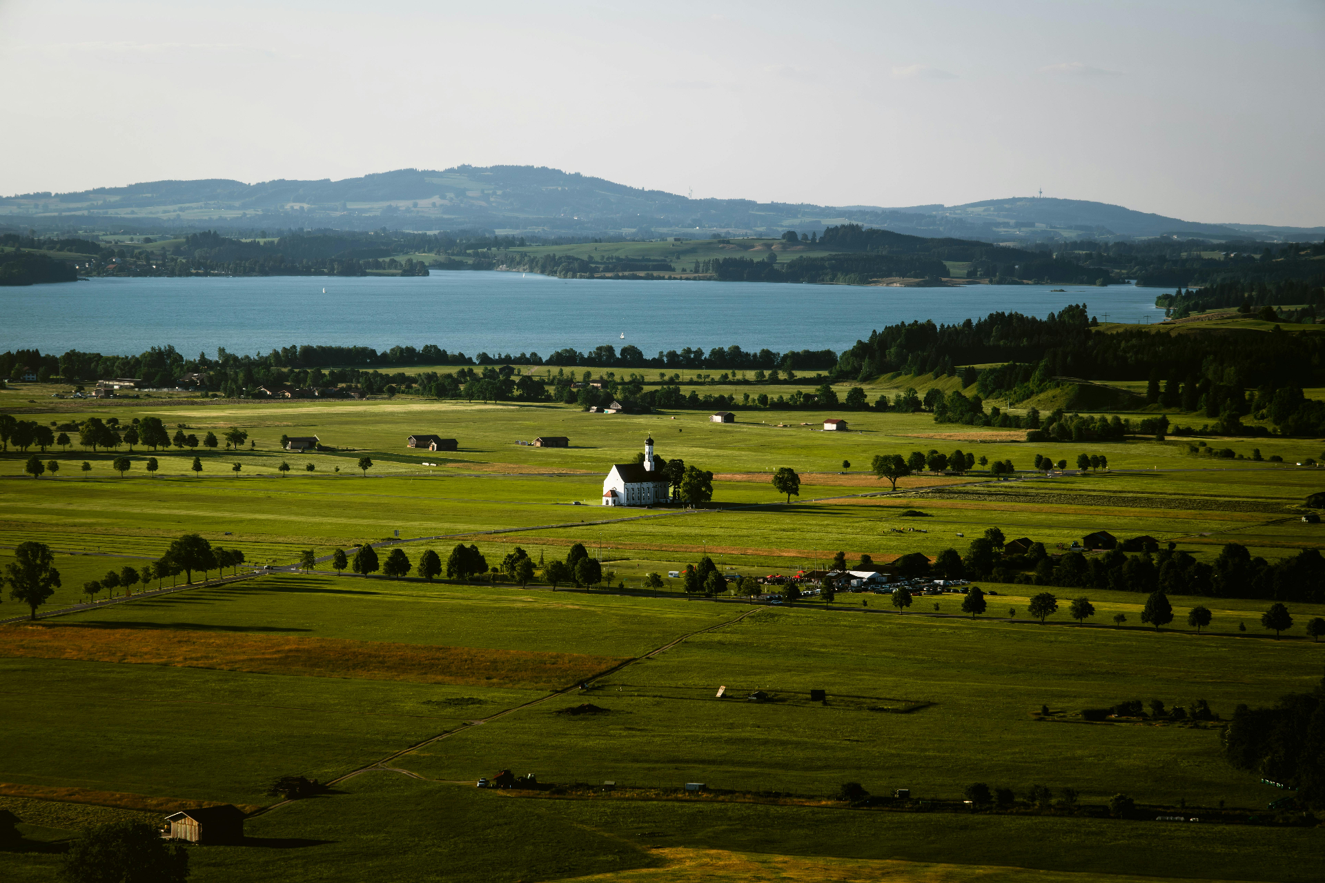 Allgäuer Panorama mit Kirche, See und Bergen im Hintergrund